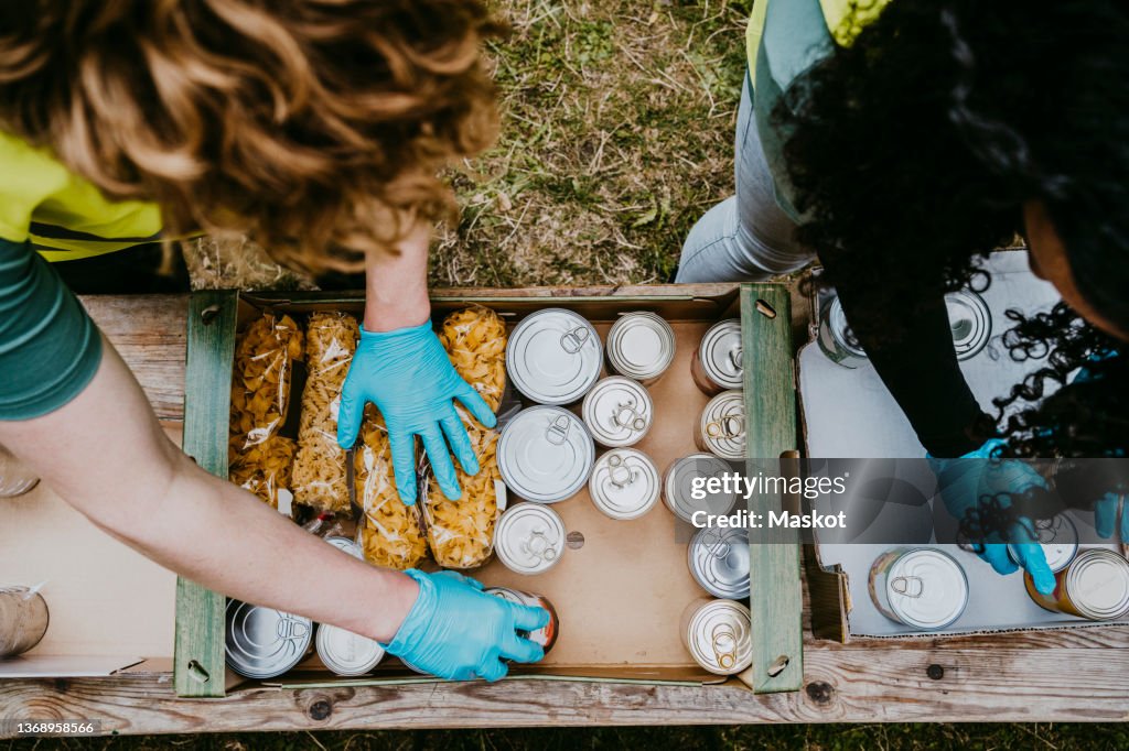 Male and female friends arranging food in cardboard boxes