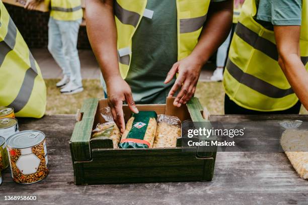 male volunteer arranging food packets in box - food pantry ストックフォトと画像