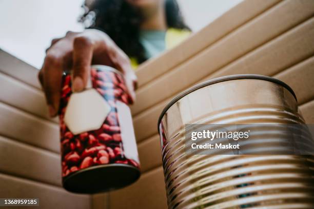 young female volunteer arranging canned food in box - canned goods stock pictures, royalty-free photos & images