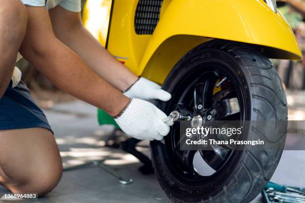 male mechanic repairing motorcycle - motorcycle tyre stock pictures, royalty-free photos & images