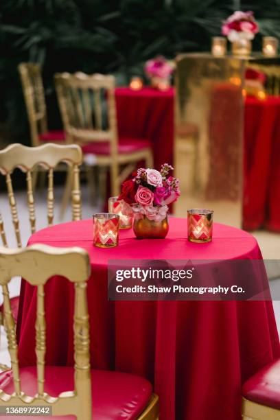 gold vase on red table clothes full of red and pink roses for a wedding rehearsal cocktail party - red gold party stock pictures, royalty-free photos & images