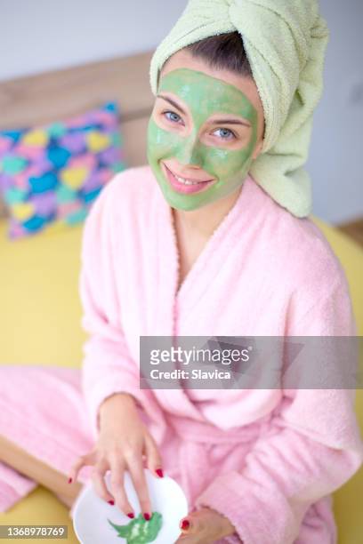woman putting facial mask on her face - face mask stock pictures, royalty-free photos & images