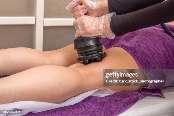 massagem vibratória é aplicada na perna da mulher com uma máquina de massagem no salão de beleza. - tighten - fotografias e filmes do acervo