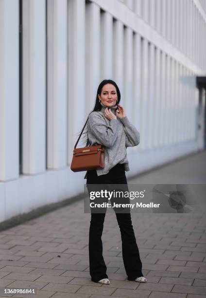 Yvonne Mouhlen wearing Aquazzura shiny silver heels, black denim jeans, Yves Saint Laurent brown leather bag and H&M grey knit turtleneck sweater on...