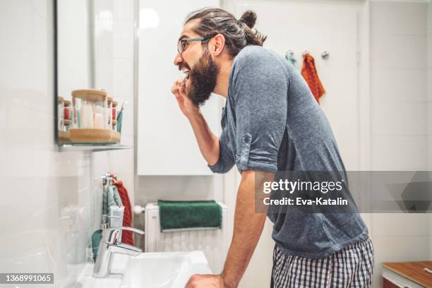 at home - young man brushing his teeth - hipster man bun stock pictures, royalty-free photos & images