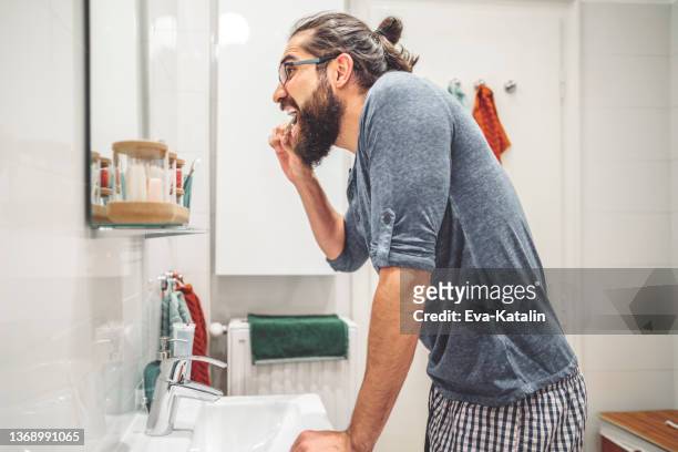 em casa-homem novo que escova seus dentes - coque masculino - fotografias e filmes do acervo