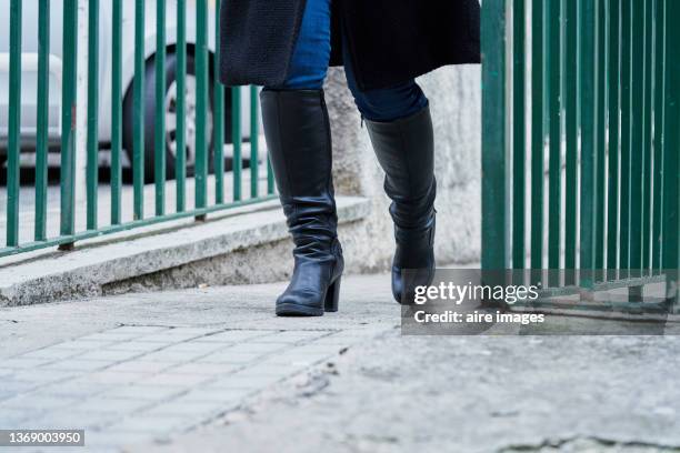 close-up of woman in leather black boots walking on the street. - black boot fotografías e imágenes de stock