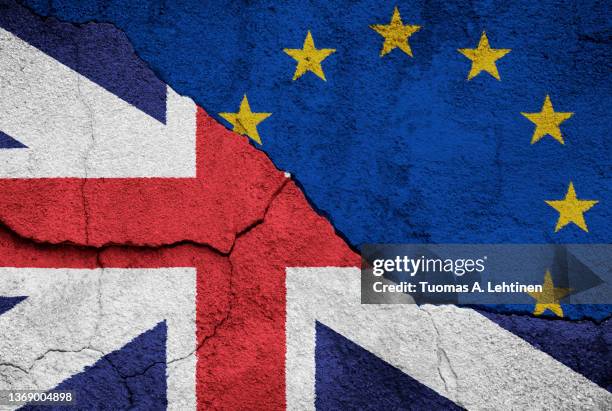 full frame photo of british (united kingdom, uk) and european union (eu) flags painted on a cracked wall. brexit concept. - brexit stock-fotos und bilder