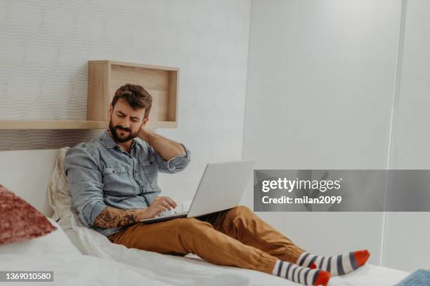 young man in the bedroom - neck pain stock pictures, royalty-free photos & images