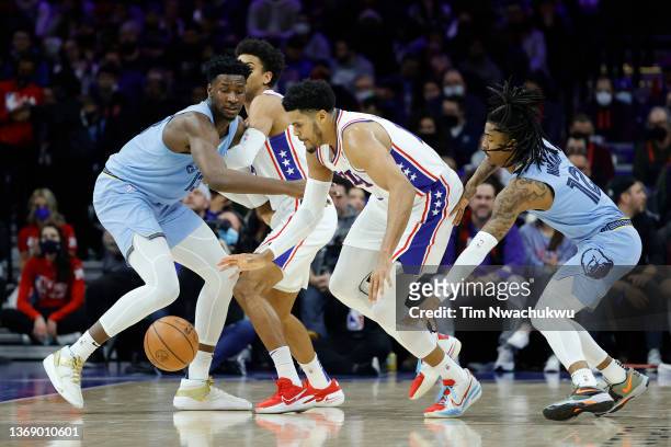 Tobias Harris of the Philadelphia 76ers tries to dribble between Jaren Jackson Jr. #13 and Ja Morant of the Memphis Grizzlies at Wells Fargo Center...