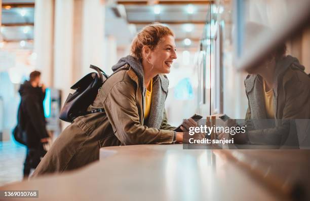 woman purchasing a train ticket at the railroad station - train ticket stock pictures, royalty-free photos & images