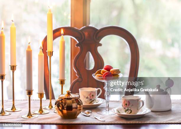 still life tea drinking. a two cups of tea with a kettle and a macarons on a wooden table. - candlestick holder stock pictures, royalty-free photos & images