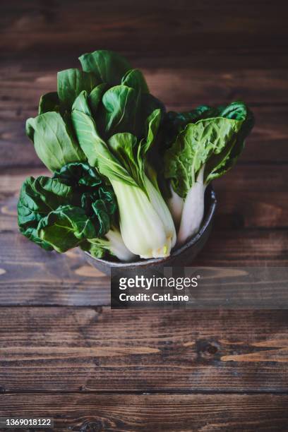 ceramic bowl filled with bok choy on a rustic wood table. space for copy - chinese cabbage stock pictures, royalty-free photos & images