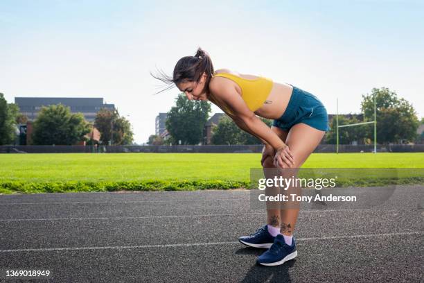 young woman athlete resting on outdoor track - atemlos stock-fotos und bilder