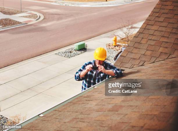 insurance agent or roofer on roof assessing damage to a roof - damaged shingles stock pictures, royalty-free photos & images
