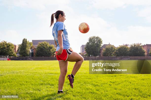 young woman playing soccer on athletic field - women's football stock pictures, royalty-free photos & images