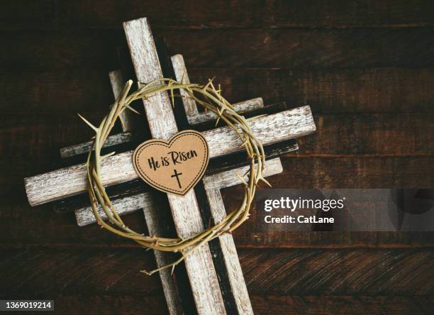 wooden cross with a crown of thorns on a rustic wood background with a message that reads he is risen. easter background - christ is risen 個照片及圖片檔