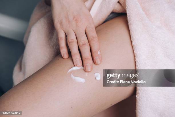 woman applies moisturizing lotion to her thigh skin,  body cream after showering - cellulite concept stock pictures, royalty-free photos & images