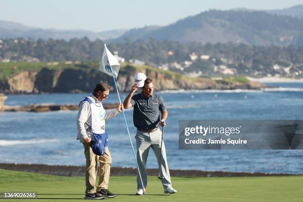 Tom Hoge of the United States celebrates with his caddie Henry Diana after finishing on the 18th green during the final round of the AT&T Pebble...