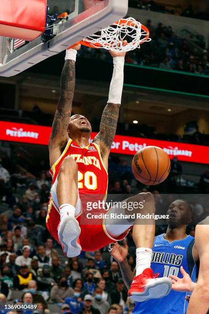 John Collins of the Atlanta Hawks hangs on the rim after a dunk against the Dallas Mavericks in the second half at American Airlines Center on...