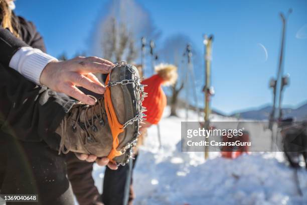 close-up of man sitting by a ski slope with crampons on hiking boots - crampon stockfoto's en -beelden