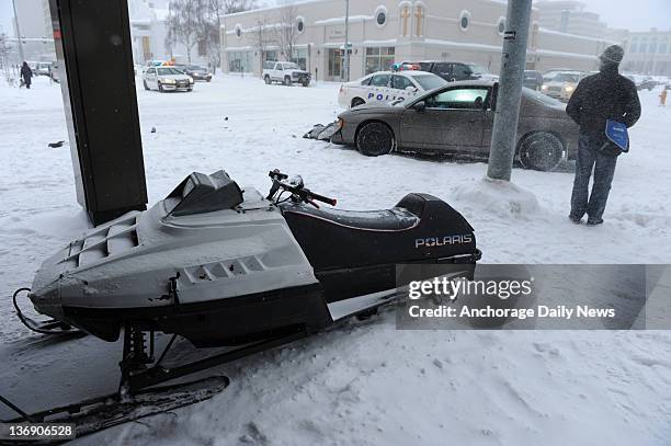 Snow machine rests on the sidewalk next to the Captain Cook Hotel after a two vehicle accident on 5th Avenue as another big snow fall hit the...