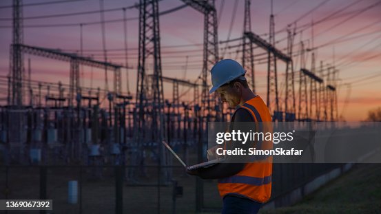 Ingeniero masculino confiado que usa una computadora portátil frente a la central eléctrica Ingeniero masculino confiado que usa una computadora portátil frente a la central eléctrica