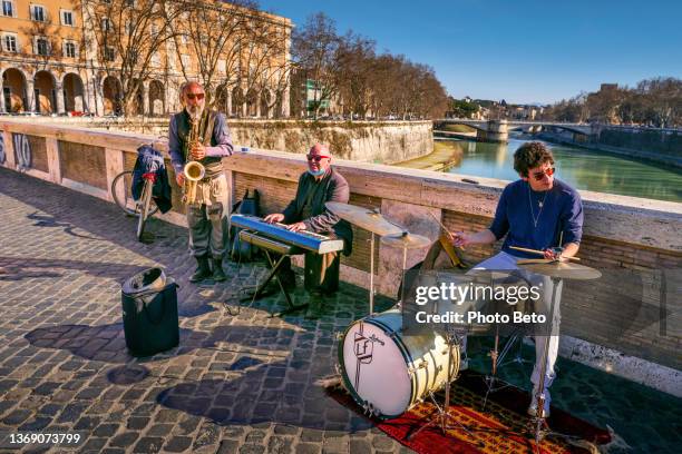 un groupe de jazz de musiciens de rue joue le long de ponte sisto dans le trastevere au cœur de rome - the fall band photos et images de collection