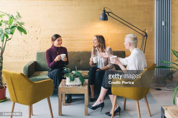 group of three happy businesswomen having a coffee break - leisure work coffee happy stockfoto's en -beelden
