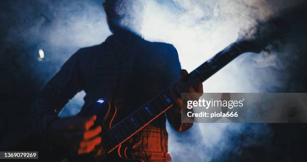 rockgitarrist spielt gitarre in einer live-show mit bühnenlichtern - electric guitar stock-fotos und bilder