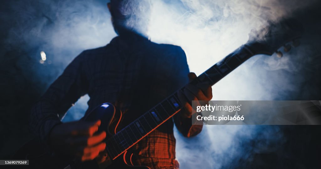 Rock guitarist playing guitar in a live show with stage lights