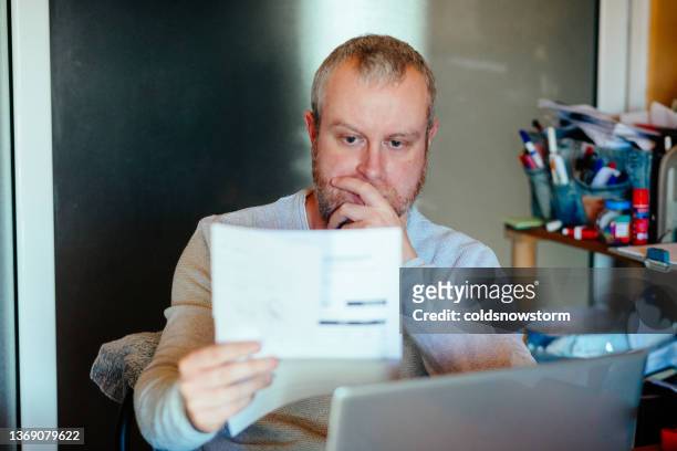 worried man checking bills at home - consumerism stock pictures, royalty-free photos & images
