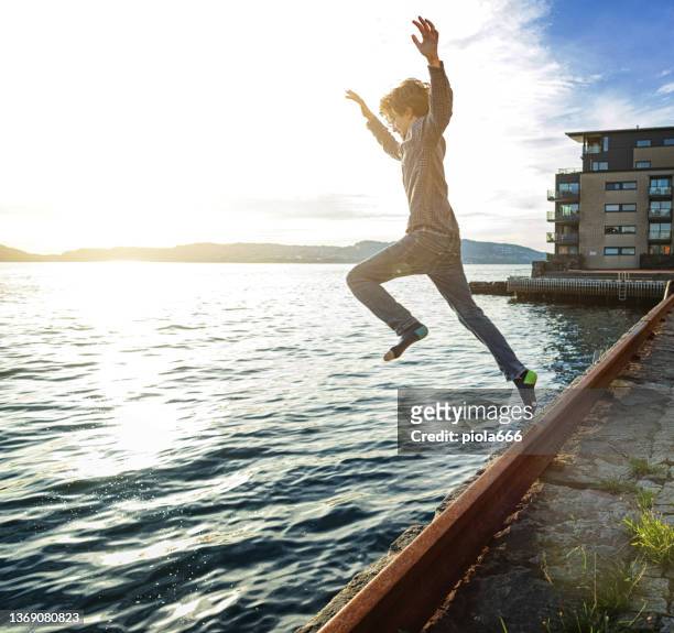 little kid jumping and diving dressed into water at sea in summer - jumping sun bildbanksfoton och bilder