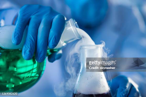 close up of pouring smoke from laboratory flask. - blue glove stock pictures, royalty-free photos & images