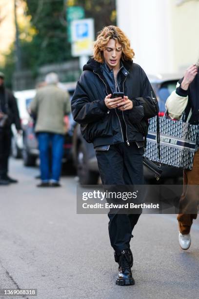 Guest wears a black shiny leather zipper jacket, a black V-neck shirt, a black nylon with sheep interior and hoodie bomber coat, black large pants,...