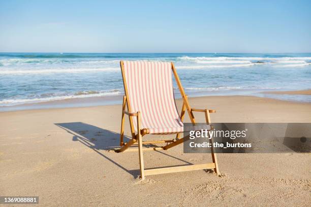 red and white striped deck chair at beach - sdraio da spiaggia foto e immagini stock