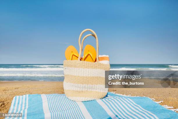 still life of beach bag by the sea against clear sky in summer - flip flops stock-fotos und bilder