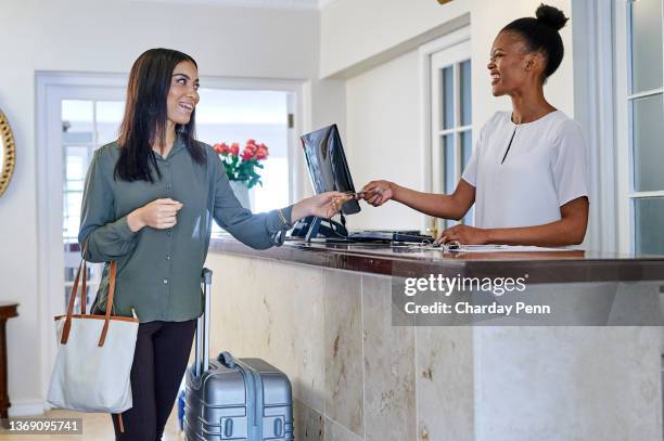 shot of a young woman standing and using her credit card to check in at the reception of a hotel - returning keys stock pictures, royalty-free photos & images
