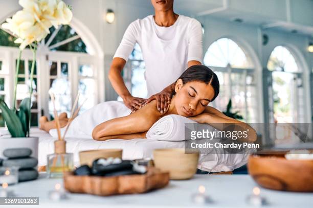 shot of an attractive young woman lying on a bed and enjoying a massage at the spa - indulgence stock pictures, royalty-free photos & images