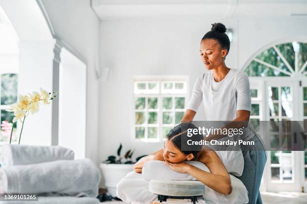 aufnahme einer jungen frau, die auf einem bett liegt und eine massage im spa genießt - masseur stock-fotos und bilder