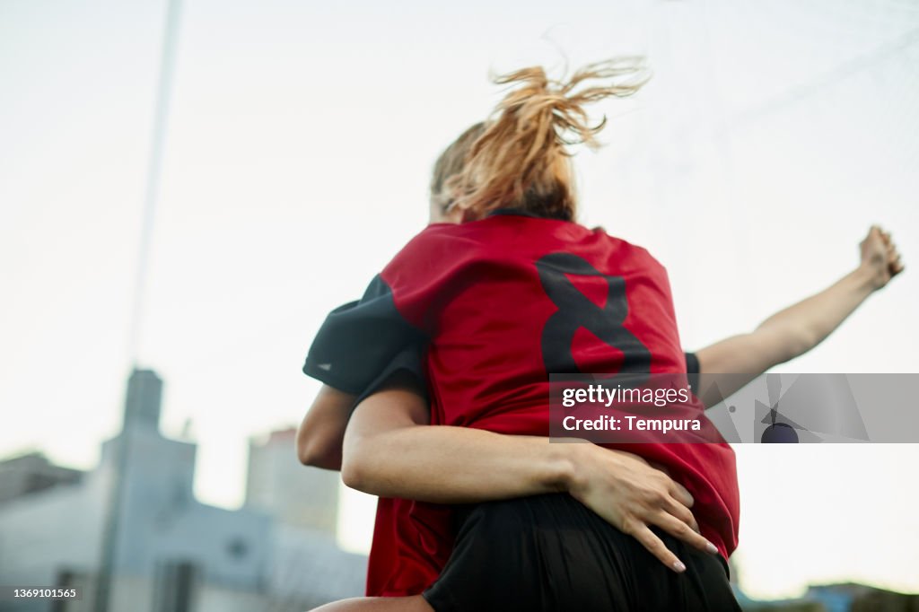 Two female soccer players celebrate a goal.