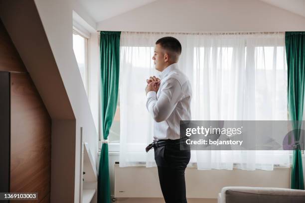 handsome young man dressing himself at home - manly room stock pictures, royalty-free photos & images