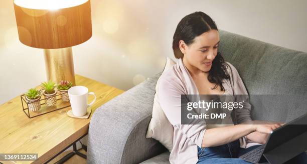 shot of a young woman using a laptop while relaxing on the couch at home - beautiful woman 40 stock pictures, royalty-free photos & images