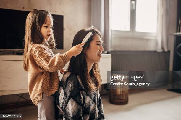 daughter combing mom's hair - combing stockfoto's en -beelden