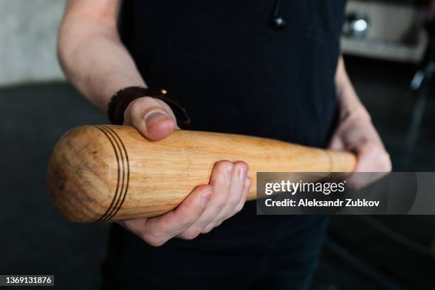 a wooden baseball bat in the hands of a man or a teenage boy, a student. the concept of sports play and leisure, entertainment and competitions, self-defense, defense and protection. - zelfverdediging stockfoto's en -beelden