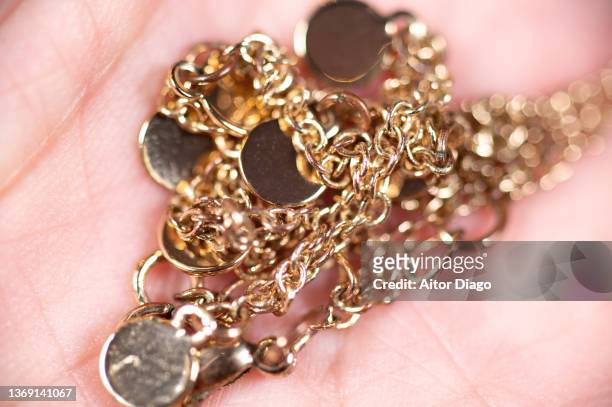 detail of a gold-colored chain on a person's hand. - gold chain stock-fotos und bilder