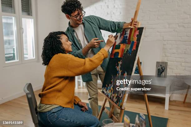 young couple enjoying spending time together painting and using technology - two artists stock pictures, royalty-free photos & images