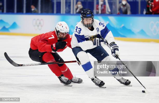 Michelle Karvinen of Team Finland skates with the puck past Lara Stalder of Team Switzerland during the third period of the Women's Preliminary Round...