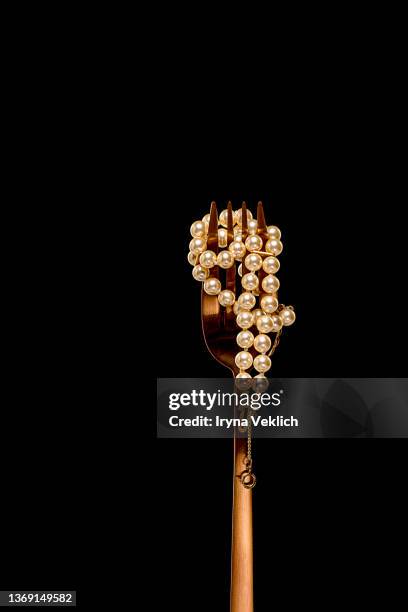 pearl  jewelry on a golden fork on a black background, macro shot. - fashion glamour pearl stock pictures, royalty-free photos & images