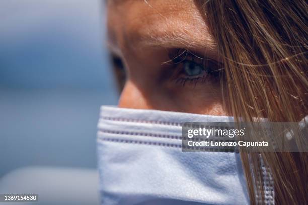 extreme close-up of woman's face wearing surgical face mask outdoors - italia corona stock pictures, royalty-free photos & images